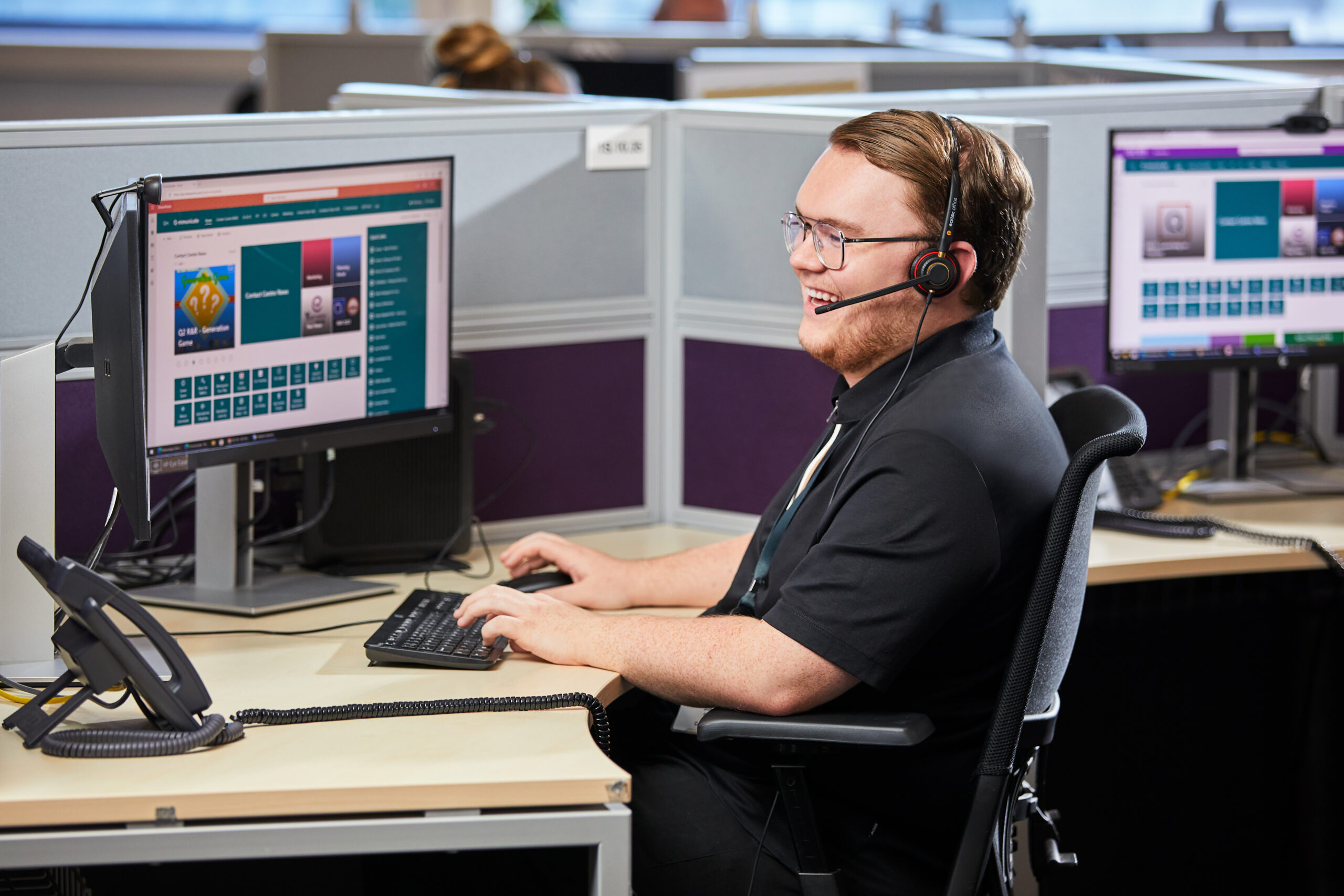 A man typing on his QVC computer wearing a headset and laughing.